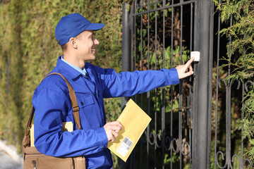 Postman with parcel ringing entrance bell outdoors