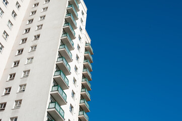 Low angle view of a high rise residential apartment block against a clear blue sky.