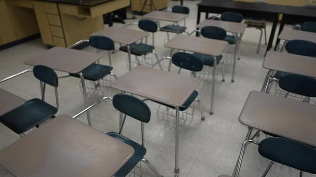 Desks arranged neatly in an empty classroom, highlighting a quiet space for education and learning. The room waits for students and teachers to begin their day.