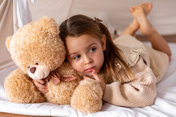 Happy 4-5 years old little girl lying in a wigwam tent, hugging soft toy teddy bear. Children's room, childhood, games, imagination. High quality photo © Irina Mikhailichenko