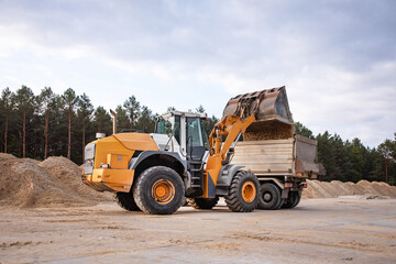 Wheel front loader or bulldozer at a construction site in a quarry. Powerful modern equipment for earthworks. Construction site.