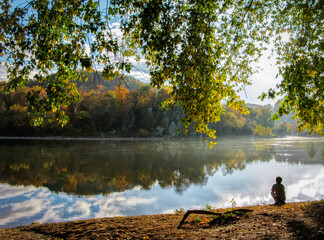 Man looking at fall reflection on the river