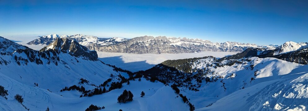 Skier drives towards the sea of fog in deep snow. Freeriding in deep snow towards Walensee and in the background the Churfirsten. High quality photo