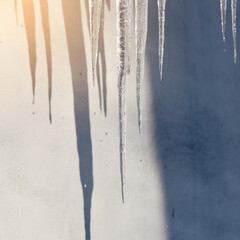Frozen icicles on roof edge, melting and dripping water as the cold winter weather gives way to...