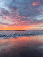 Vibrant sunset reflects on tranquil ocean waves at serene beach location