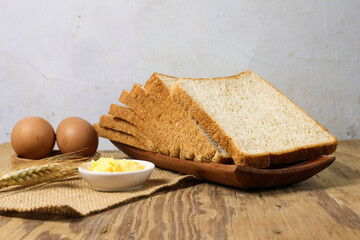 Sliced Wheat Bread, Butter, Eggs, and Wheat on Wooden Table