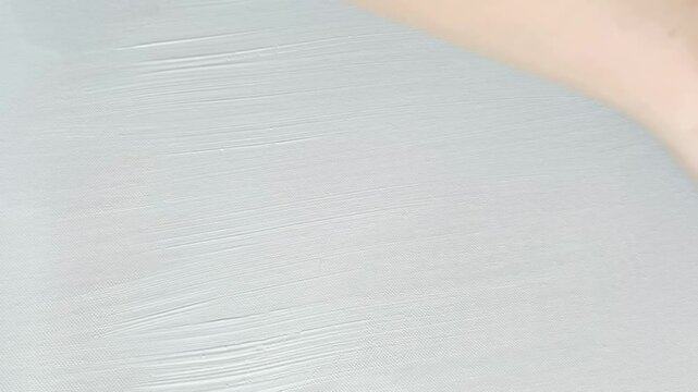 Creating art with brushstrokes applying white paint on canvas in slow motion for creative expression and textural techniques.