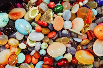 A vibrant assortment of polished gemstones in various shapes, colors, and patterns, reflecting light beautifully.