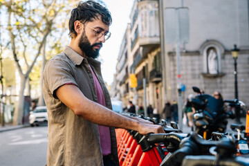 Young man unlocking electric scooter in sharing parking lot in barcelona © Guillem de Balanzó