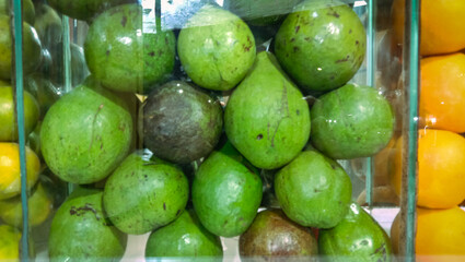 The pile of avocados and oranges on the right are prepared for juicing, a tropical fruit with natural freshness.