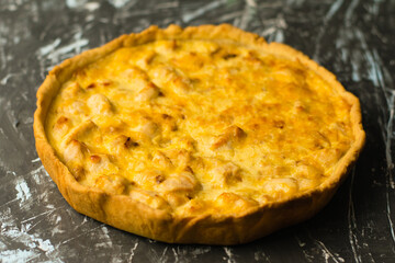 Delicious French quiche pie with chicken and cheese on a dark background with place for text, copy space. Concept of food blog, writing recipes.