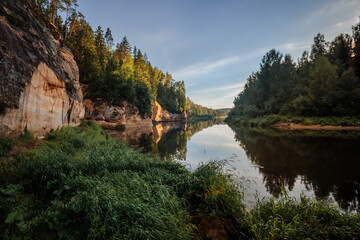 Fototapeta premium eagle cliffs near Cēsis on a sunny summer evening after rain with a reflection in the river.