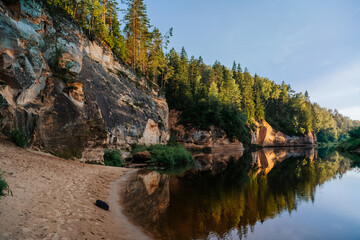 Fototapeta premium eagle cliffs near Cēsis on a sunny summer evening after rain with a reflection in the river.