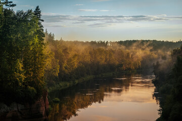 scenic view of the river where the background is forests over forests fog and the evening sun shines