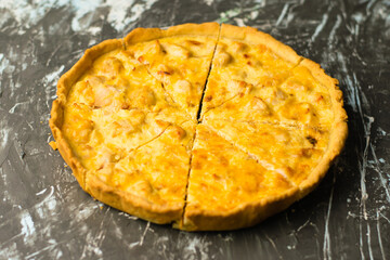 Delicious French quiche pie with chicken and cheese cut into pieces, on a dark background with place for text, copy space. Food blog concept, writing recipes
