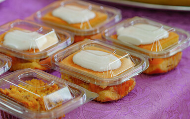 Packaged desserts with cream topping in transparent containers on a purple tablecloth, ideal for takeout, food delivery, catering services, events, bakeries, and homemade dessert businesses.