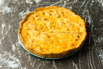Delicious French quiche pie with chicken and cheese cut into pieces, on a dark background with place for text, copy space. Food blog concept, writing recipes