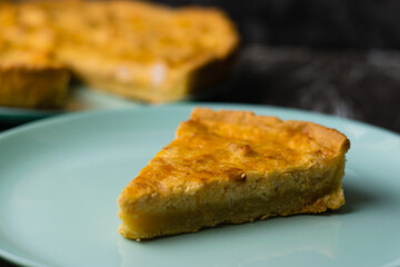 Piece of delicious open pie quiche with chicken, cheese and cream on a turquoise plate, copy space....