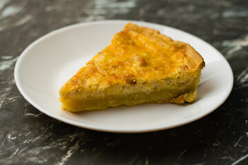 Piece of delicious open pie quiche with chicken, cheese and cream on a white plate, copy space. Food blog concept, recipe writing.