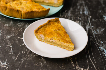 Piece of delicious open pie quiche with chicken, cheese and cream on a white plate, copy space. Food blog concept, recipe writing.
