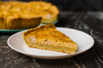 Piece of delicious open pie quiche with chicken, cheese and cream on a white plate, copy space....