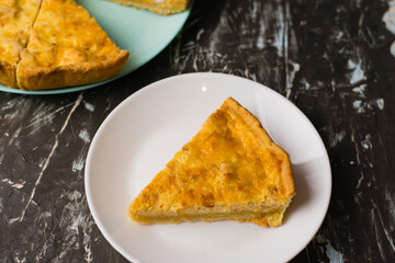 Flatlay, a piece of delicious open-faced quiche pie with chicken, cheese and cream on a white plate. Concept of food blog, writing recipes.