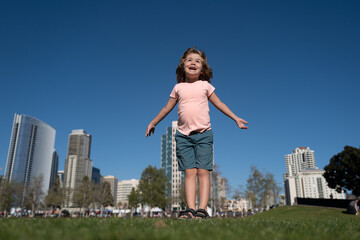 Kid run on city park. Lifestyle portrait of cute kid outdoors. Summer kids outdoor portrait. Close-up face child playing outdoors in summer park. Kid having fun outdoor on sunny summer day.