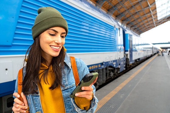 A woman traveller checking her smartphone at the train station, preparing for her next adventure