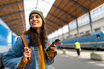 A modern traveller, a young woman with a backpack, using her smartphone to plan her next steps at...