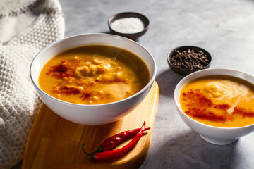 Pumpkin soup served on the table. Pumkin cream soup with rusks. Cozy atmophere at home. Staying at home and eating homemade food, nesting concept
