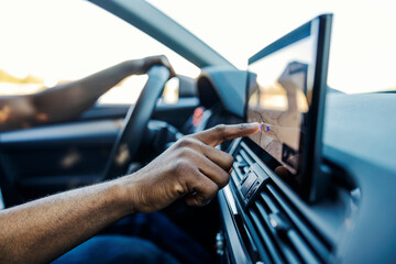 Close up of black driver's hand scrolling on GPS display in a car.
