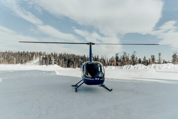 Tourist civilian small helicopter taking off, snowy winter, mountain background