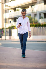 Fototapeta premium Man walking outdoors while using smartphone