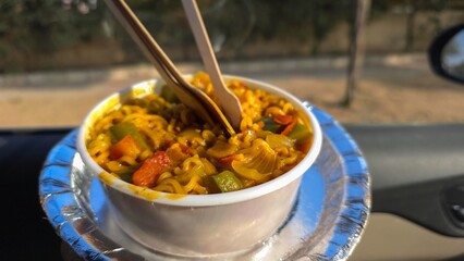 Roadside maggi food eating in car. Mix veg tadka maggi served with spoons