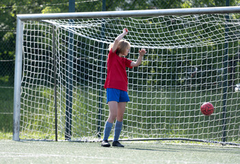 Obraz premium Girl Goalkeeper Stands At Goalposts During Children'S Football Match
