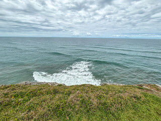 View of the rough ocean from the shore with coastal vegetation - Torres, Brasil