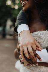 Close-Up of Intertwined Hands of a Bride and Groom Highlighting Lace Wedding Dress and Emotional Connection