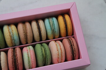 Macarons in different colors and tastes in the pink box