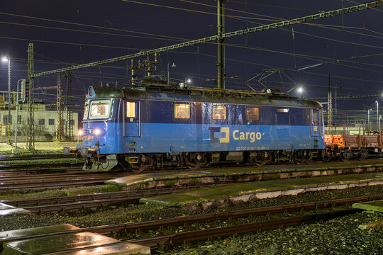 An electric locomotive from the carrier CD Cargo pulls a freight train through the Nymburk railway station, exuding the industrial charm of rail transport.
