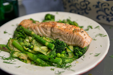 Pan fried salmon with warm green spring salad, fresh and healthy lunch, close up