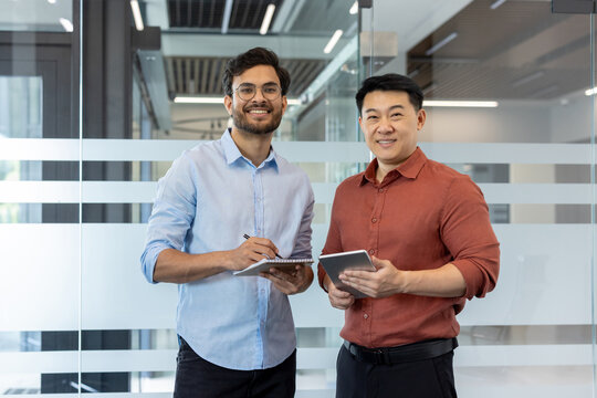 Portrait of two diverse colleagues, male office workers smiling and looking at camera, business people in casual clothes.