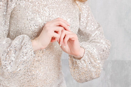 A woman with beautiful hands wearing a silver sequined dress.