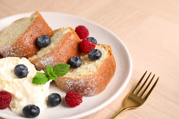 Pieces of freshly baked sponge cake, berries, ice cream and mint on wooden table, closeup