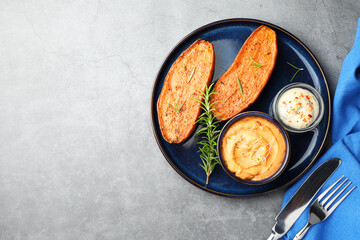 Halves of tasty baked sweet potato served on grey textured table, flat lay