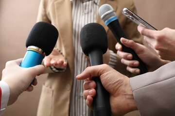 Group of journalists interviewing businesswoman on beige background, closeup