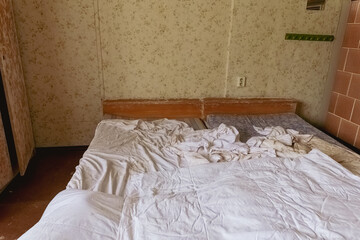 Messy bedroom with unmade beds and floral wallpaper in a vintage setting