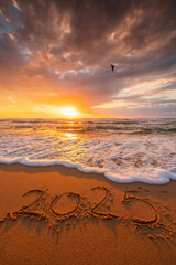 Happy New Year 2025 concept, lettering on the beach. Written text on the sea beach at sunrise...