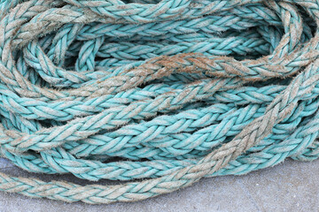 Docking rope grunge texture. Coiled, weathered and dirty string on a ship deck. Industrial, nautical scene. Strength and wear of a used mooring line. Rugged, rough appearance.