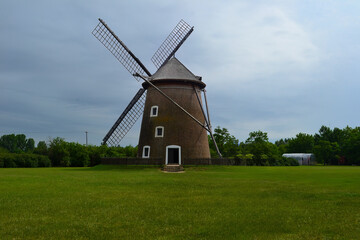 Obraz premium Traditional Windmill with Wooden Blades in a Rural Grassy Field