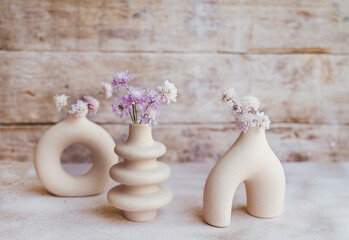 Modern beige ceramic small vases with pink flowers . Scandinavian interior style 